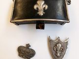 un sac à main noir orné d'une couronne, à côté de deux autres objets