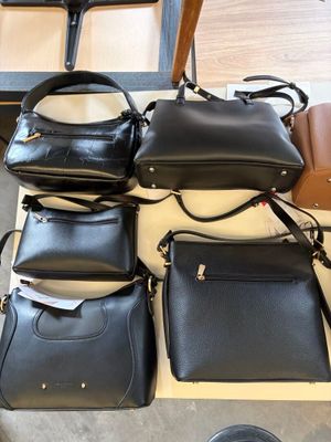several black leather handbags on a table in a room