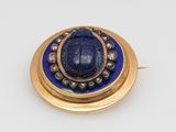 a close up of a blue and gold broochle on a white surface