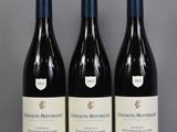 three bottles of red wine sit on a glass table