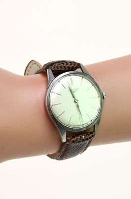une personne tient une montre à son poignet, sur un fond blanc