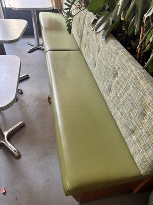 un banc vert au milieu d'une pièce avec des tables et des chaises