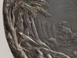 a silver plate with a picture of people and animals on it