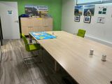 a long table with green chairs and a map on the wall