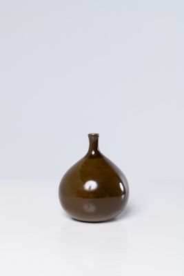 un petit vase brun posé sur une surface blanche