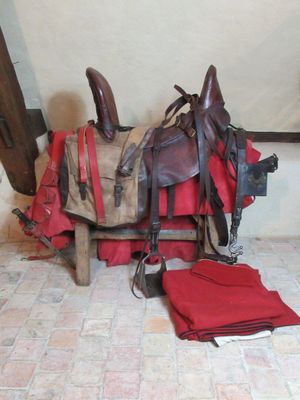 a horse saddle with a red blanket and a pair of boots