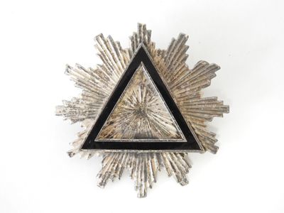 silver and black triangle shaped brooch with a starburst in the middle