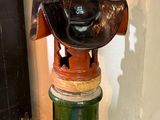 a green vase with a hat on top of it