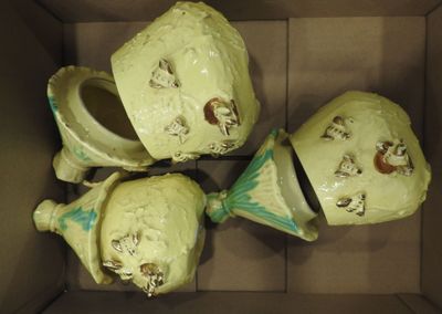 three green vases in a cardboard box with faces painted on them
