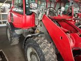 a red tractor parked in a garage with other red tractors