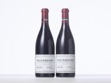 two bottles of red wine sitting on top of a table