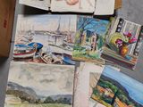 une boîte remplie de tableaux variés, posée par terre