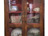 une armoire en bois avec des portes vitrées, sur laquelle sont disposés de la vaisselle