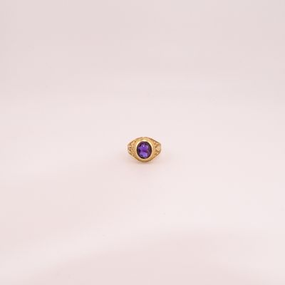 gros plan d'une bague en or avec une pierre violette