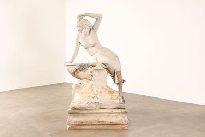 statue d'une femme assise sur un rocher dans une pièce blanche