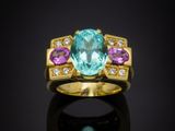 une bague en or sertie d'une topaze bleue et de saphirs roses