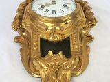 a gold clock on a white table with a white background