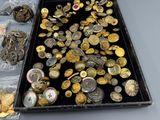 a tray full of gold and silver buttons on a table