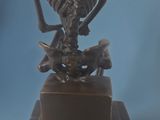 a bronze statue of a skeleton sitting on top of a box