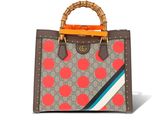 un sac à main marron et rouge avec une poignée en bambou sur fond blanc