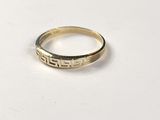 a gold ring with a greek design on it