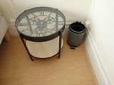 a glass table with a clock on it next to a trash can