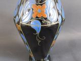 un vase noir orné de fleurs bleues et orange