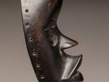 a close up of a sculpture of a face on a metal stand