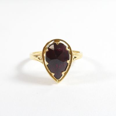 gros plan d'une bague en or avec une pierre rouge