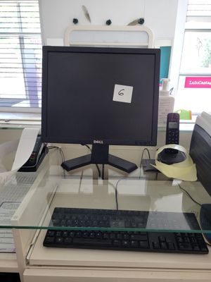 a glass desk with a computer monitor and keyboard on it