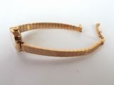 a close up of a gold bracelet on a white surface