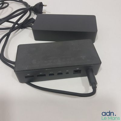 une multiprise noire branchée sur un chargeur posé sur une table blanche