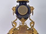 a gold and blue vase sitting on top of a wooden stand