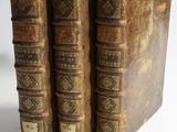 two old books sitting on top of each other on a white surface