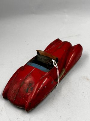 une petite voiture rouge posée sur une surface blanche