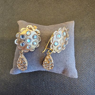 un gros plan sur une paire de boucles d'oreilles posées sur un oreiller