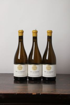trois bouteilles de vin sont alignées sur une table en bois
