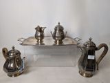 three silver teapots and a tray on a table