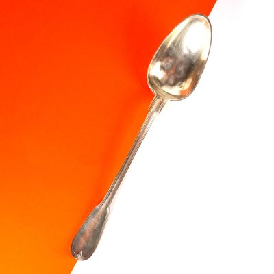 une cuillère en argent sur un fond orange et blanc