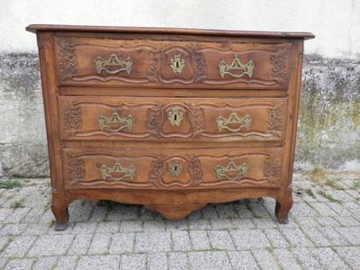 une commode en bois posée sur un sol pavé