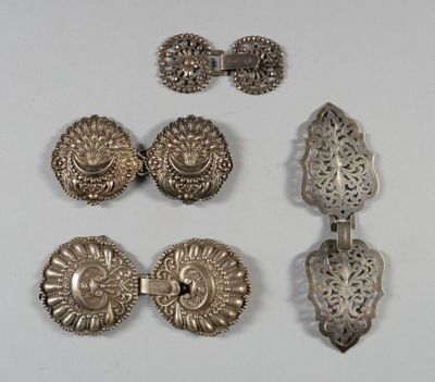 trois bijoux en argent posés sur un fond blanc