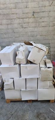 une pile de cartons posée sur une palette devant un mur de briques