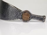 silver cuff bracelet with a wooden button on a white surface