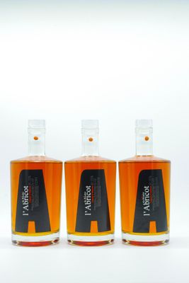 trois bouteilles de whisky posées les unes à côté des autres sur une surface blanche