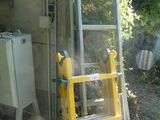une échelle appuyée contre un immeuble, à côté de toilettes