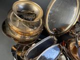 a lot of silver plates and silver dishes on the table