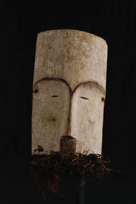un masque en bois surmonté d'un nid d'oiseau