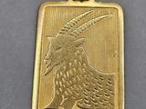 a close up of a gold pendant with a bird on it