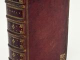 an old leather book with gold trimmings on a white surface