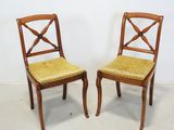 two wooden chairs with yellow upholstered seats against a white wall